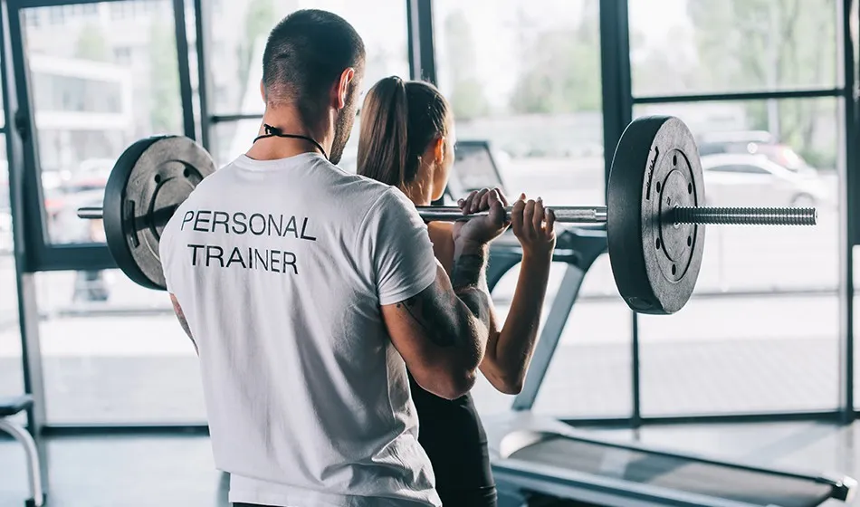 A personal trainer coaching a client through a barbell lift