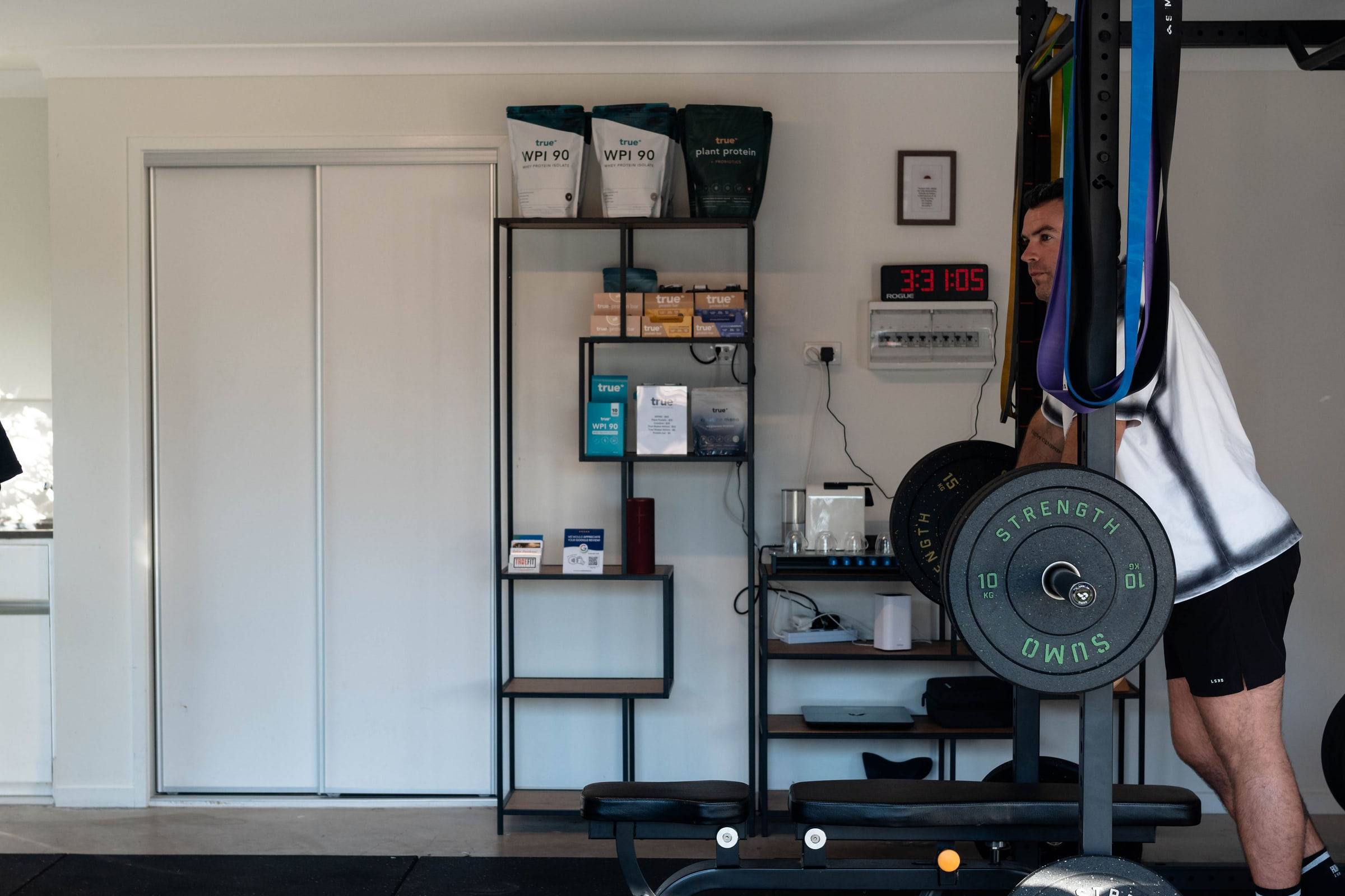 The True Fit home gym with squat rack, bench and supplement shelves