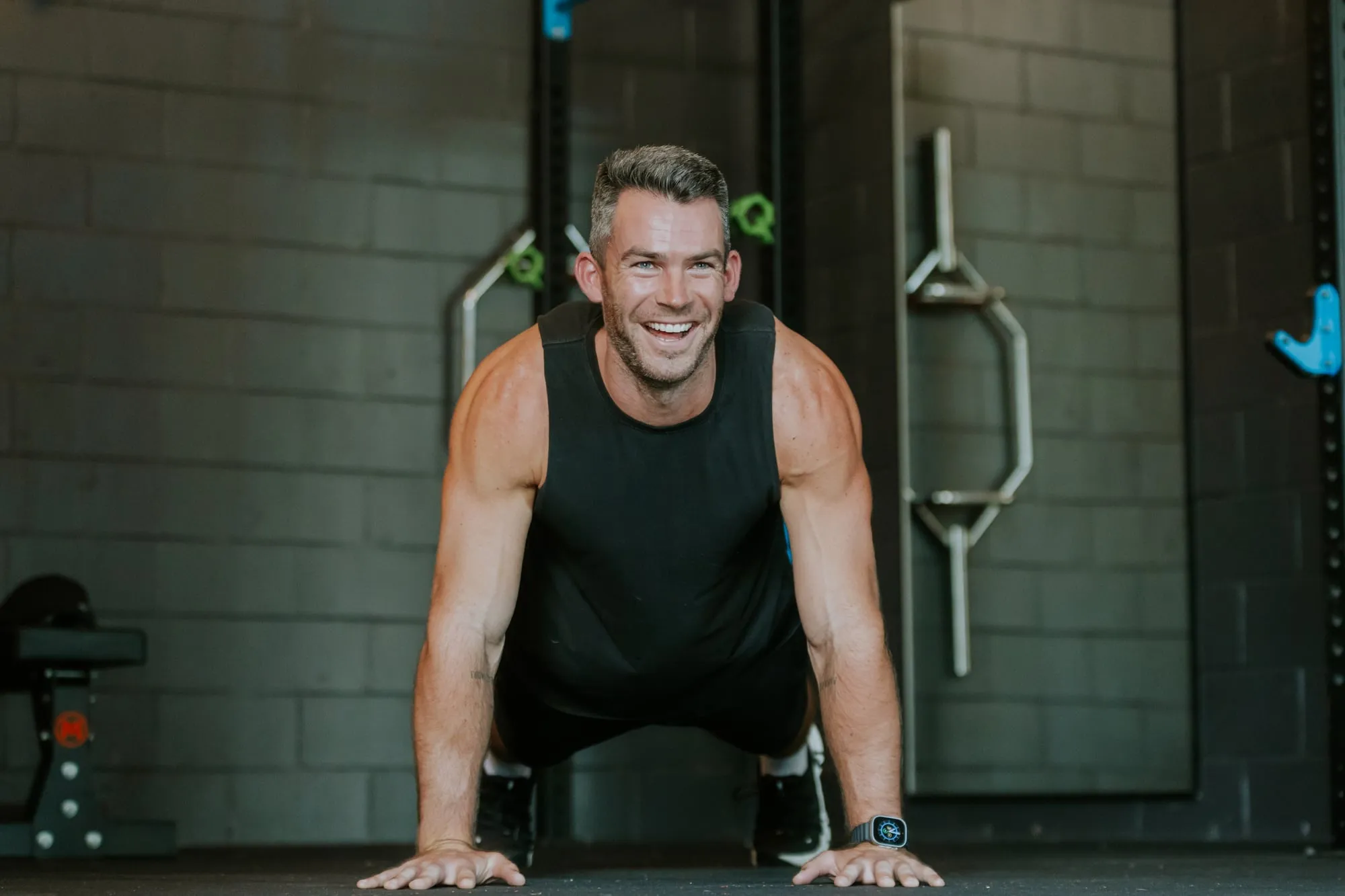 Richard smiling in a push-up position on the gym floor