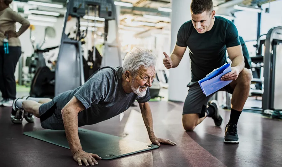 Senior man working with a personal trainer during an outdoor fitness session on the Sunshine Coast.