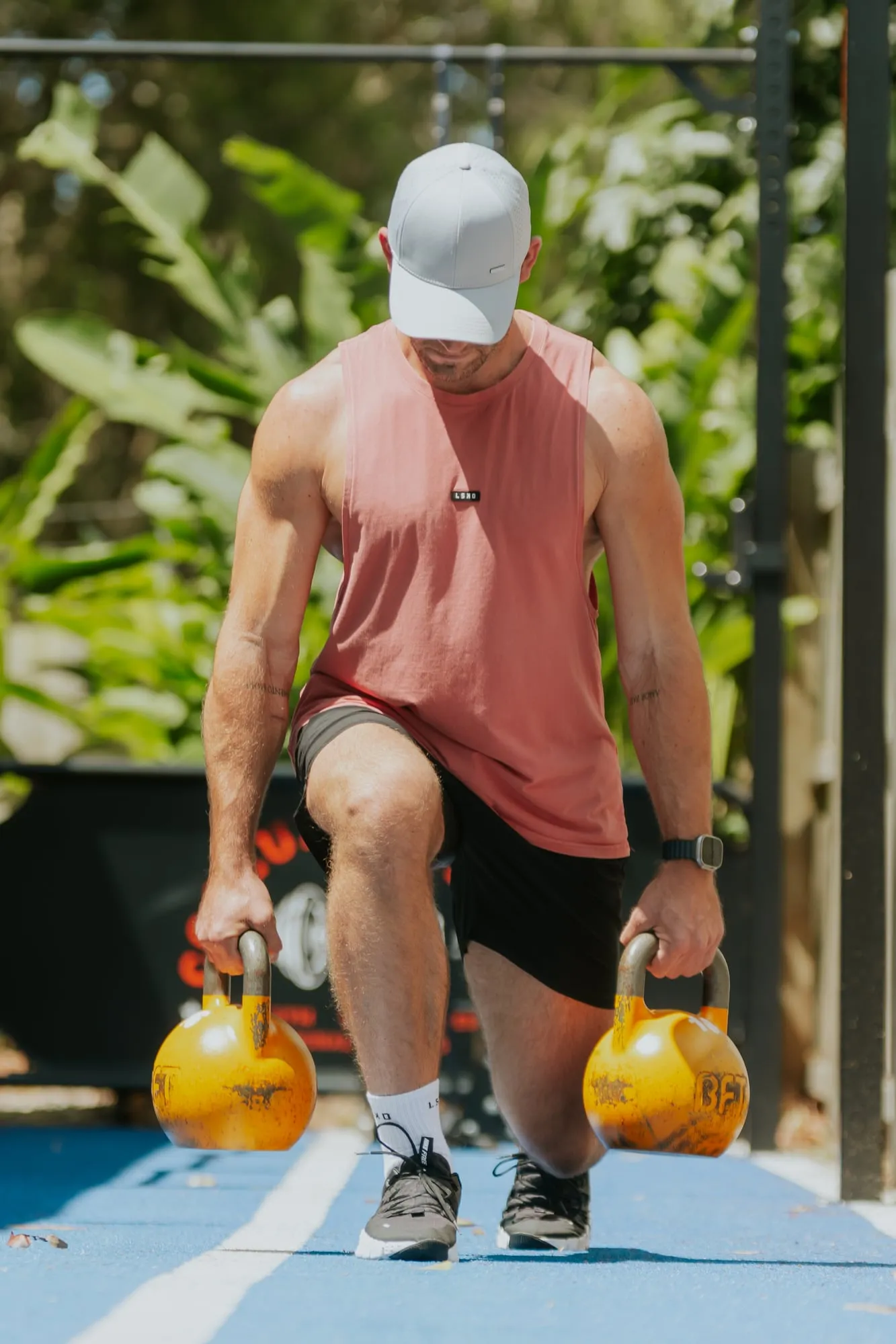 Richard doing a kettlebell lunge on an outdoor turf track
