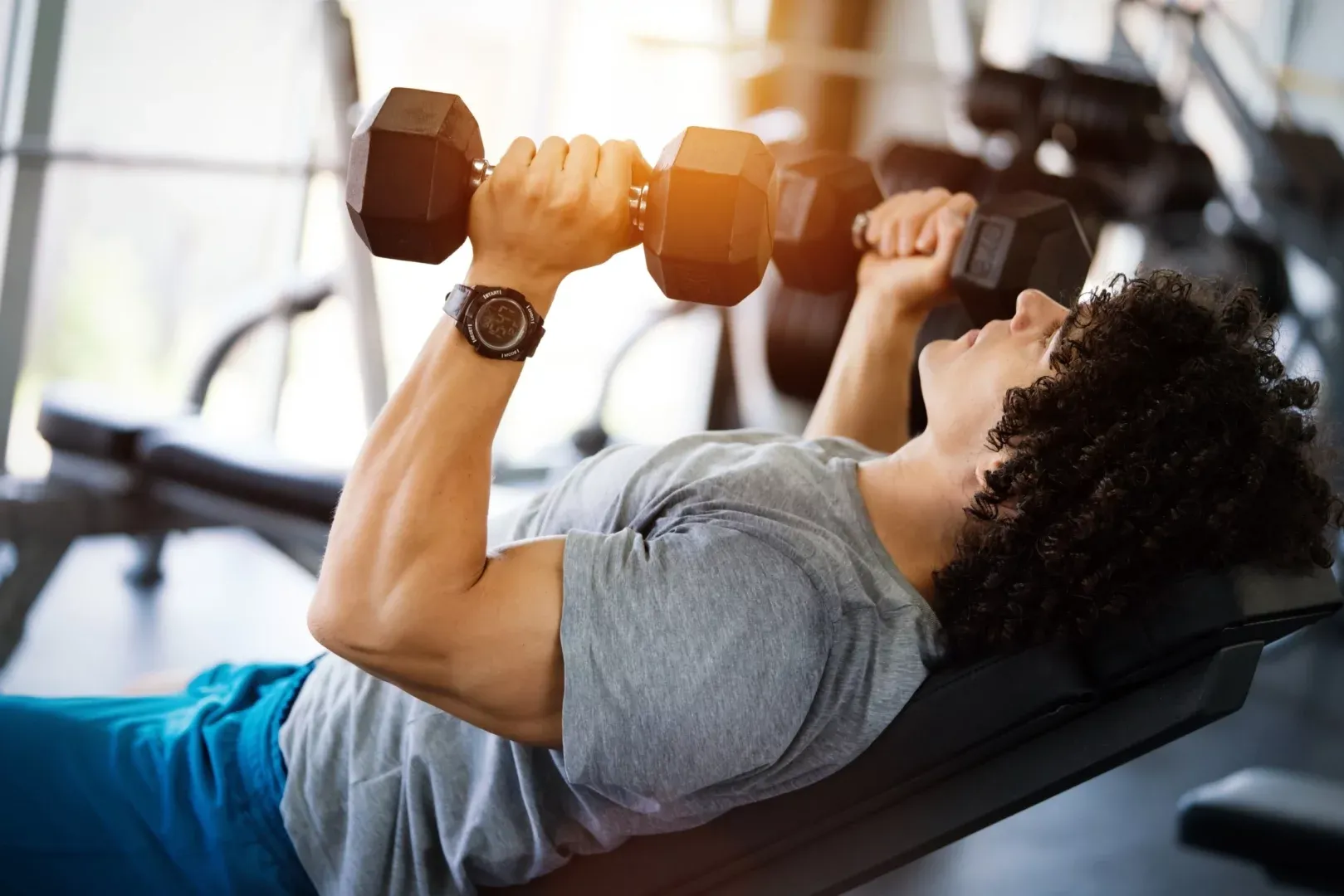 A person performing an incline bench press with dumbbells in a gym, focusing on upper chest development and shoulder stability