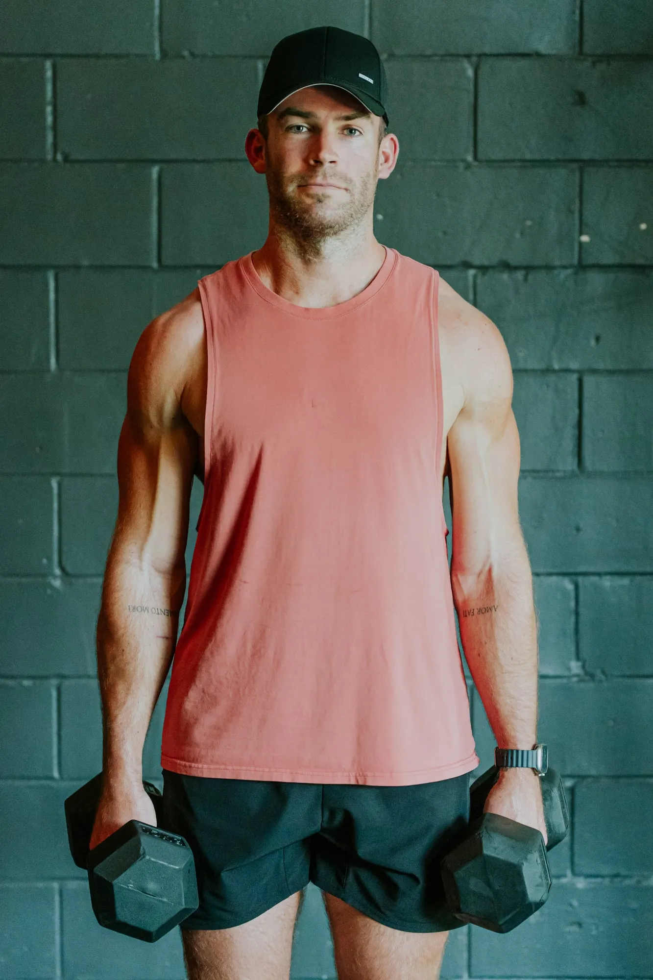 Richard holding a pair of dumbbells against a brick wall